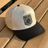 White and black cap with pickleball design on a wooden surface